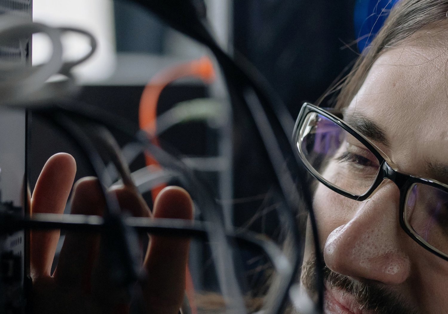 A technician working through the cabling at the back of a server rack
